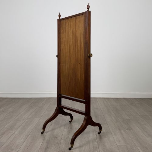 fig 5. An Edwardian mahogany full-length cheval mirror featuring a rectangular tilting glass frame supported by a wooden upright stand with finials and splayed feet on brass castors.