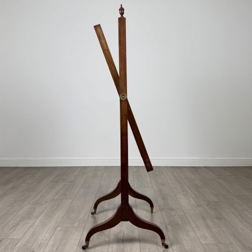 fig 7. An Edwardian mahogany full-length cheval mirror featuring a rectangular tilting glass frame supported by a wooden upright stand with finials and splayed feet on brass castors.
