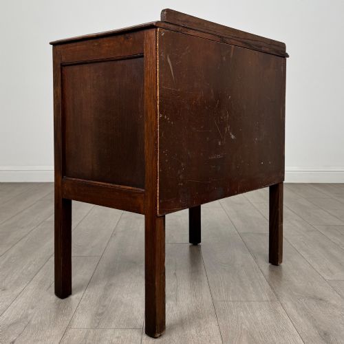 fig 3. A two-drawer golden oak chest of drawers featuring decorative metal drop handles and straight square legs.