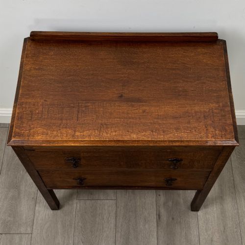 fig 8. A two-drawer golden oak chest of drawers featuring decorative metal drop handles and straight square legs.
