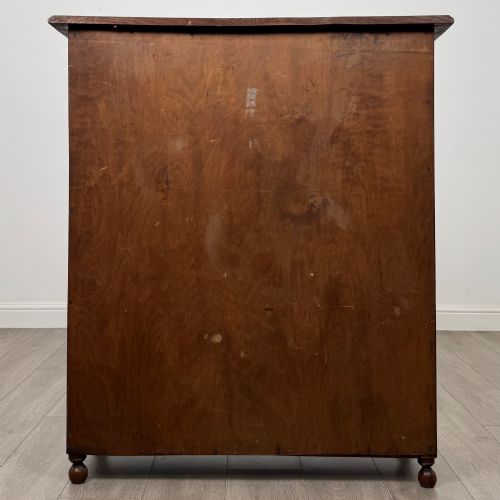 fig 5. An Edwardian warm brown oak display cabinet featuring twin leaded glass doors with a geometric pattern, interior wooden shelves, and rounded bun feet.