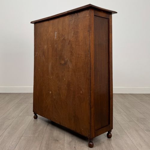 fig 6. An Edwardian warm brown oak display cabinet featuring twin leaded glass doors with a geometric pattern, interior wooden shelves, and rounded bun feet.