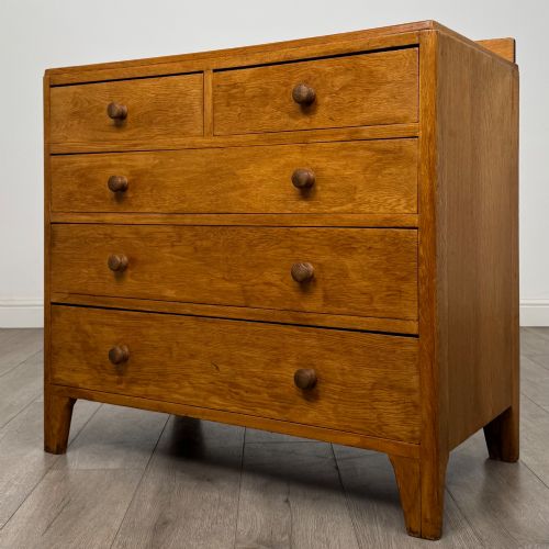 fig 1. An antique golden oak chest of drawers featuring two short drawers above three long drawers with turned wooden knobs.