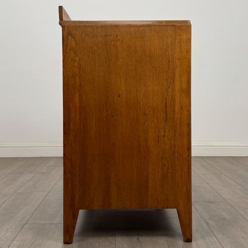 fig 6. An antique golden oak chest of drawers featuring two short drawers above three long drawers with turned wooden knobs.