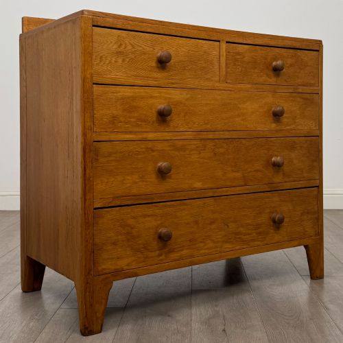 fig 7. An antique golden oak chest of drawers featuring two short drawers above three long drawers with turned wooden knobs.
