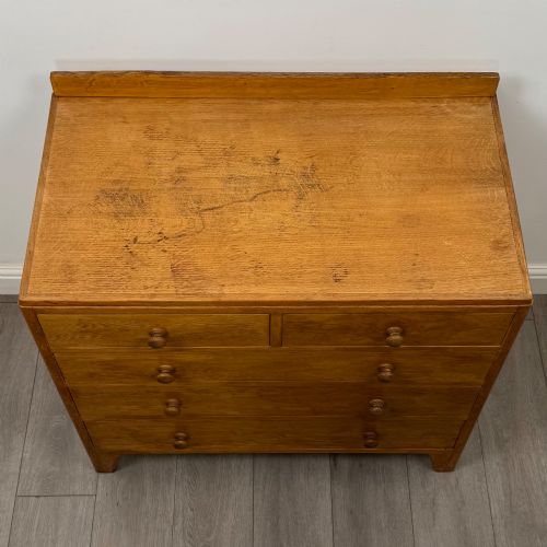 fig 8. An antique golden oak chest of drawers featuring two short drawers above three long drawers with turned wooden knobs.