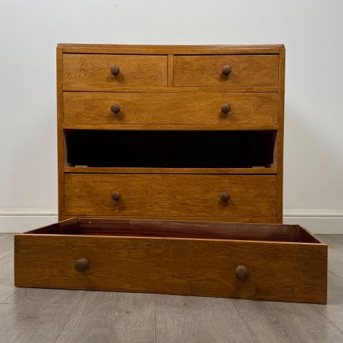 fig 9. An antique golden oak chest of drawers featuring two short drawers above three long drawers with turned wooden knobs.