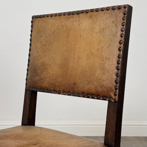 fig 5. A set of six Edwardian dark oak dining chairs with tan studded leather upholstery, comprising two carver armchairs and four side chairs featuring turned legs.