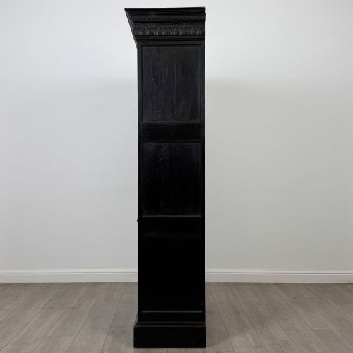 fig 3. A single-door dark oak Victorian wardrobe featuring geometric panel mouldings, a carved relief face in a central diamond, and a pronounced decorative cornice.