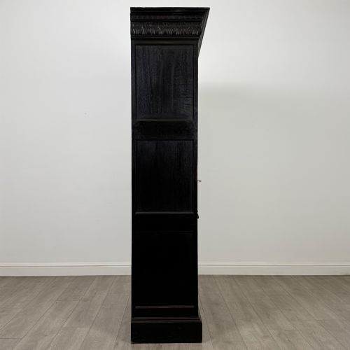 fig 7. A single-door dark oak Victorian wardrobe featuring geometric panel mouldings, a carved relief face in a central diamond, and a pronounced decorative cornice.