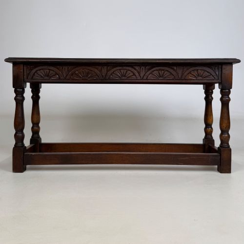 fig 4. A dark carved oak bench featuring turned legs, a lower box stretcher, and a carved lunette frieze along the apron.