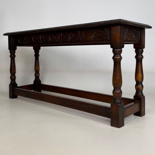 fig 5. A dark carved oak bench featuring turned legs, a lower box stretcher, and a carved lunette frieze along the apron.