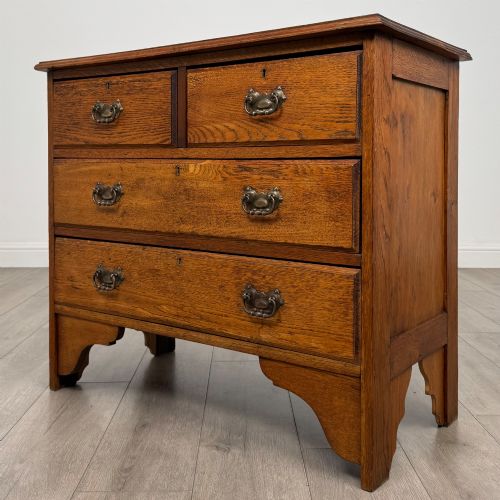 fig 1. An Edwardian warm brown oak chest of drawers featuring two short upper drawers and two long lower drawers with brass drop handles.