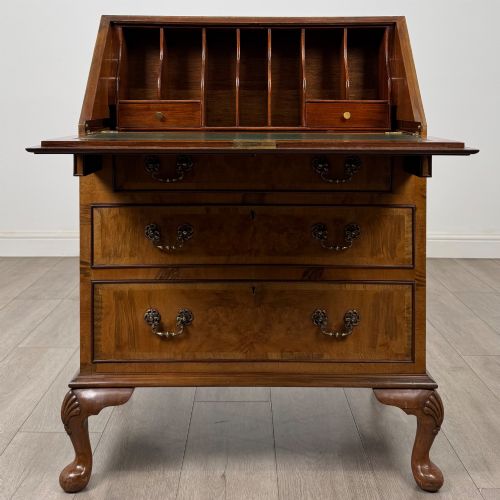 fig 1. An Edwardian burr walnut writing bureau featuring a sloping fall front, three drawers with decorative brass handles, and cabriole legs.