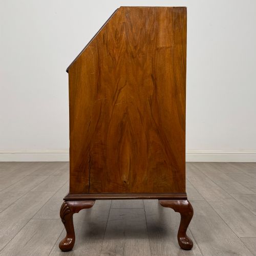 fig 3. An Edwardian burr walnut writing bureau featuring a sloping fall front, three drawers with decorative brass handles, and cabriole legs.