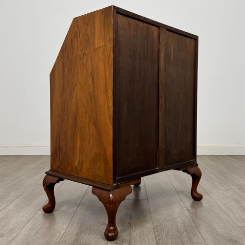 fig 4. An Edwardian burr walnut writing bureau featuring a sloping fall front, three drawers with decorative brass handles, and cabriole legs.