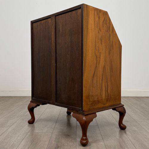 fig 6. An Edwardian burr walnut writing bureau featuring a sloping fall front, three drawers with decorative brass handles, and cabriole legs.