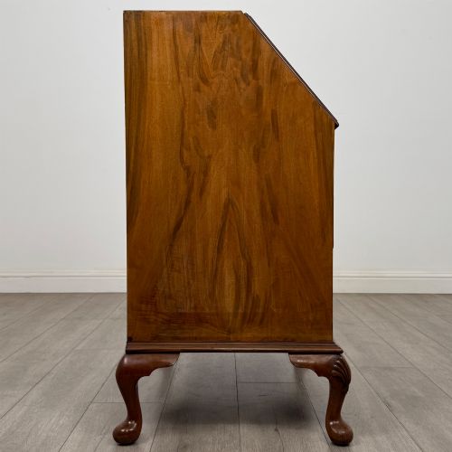 fig 7. An Edwardian burr walnut writing bureau featuring a sloping fall front, three drawers with decorative brass handles, and cabriole legs.