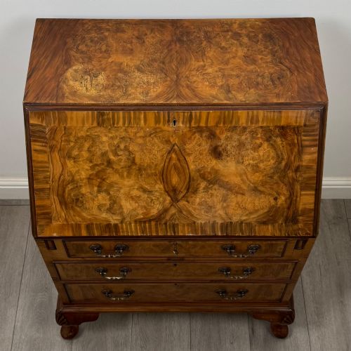 fig 9. An Edwardian burr walnut writing bureau featuring a sloping fall front, three drawers with decorative brass handles, and cabriole legs.