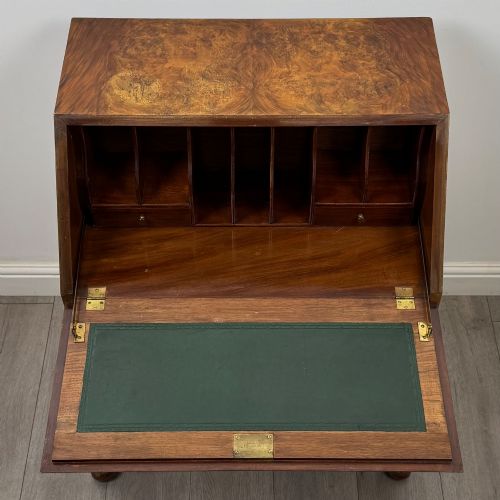 fig 10. An Edwardian burr walnut writing bureau featuring a sloping fall front, three drawers with decorative brass handles, and cabriole legs.