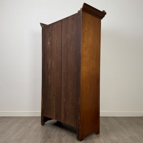 fig 6. An Edwardian walnut wardrobe featuring a central mirrored door flanked by carved timber panels above a single base drawer.