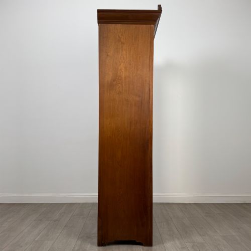 fig 7. An Edwardian walnut wardrobe featuring a central mirrored door flanked by carved timber panels above a single base drawer.
