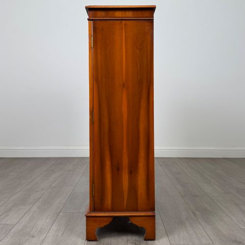 fig 4. An antique yew wood display cabinet featuring two astragal glazed doors with geometric glazing bars, housing books on internal shelves, and resting on bracket feet.