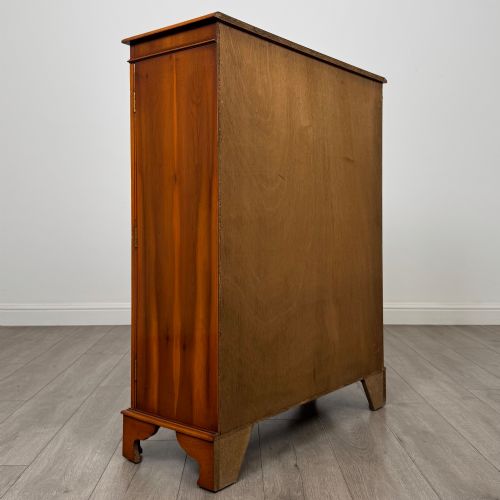 fig 5. An antique yew wood display cabinet featuring two astragal glazed doors with geometric glazing bars, housing books on internal shelves, and resting on bracket feet.