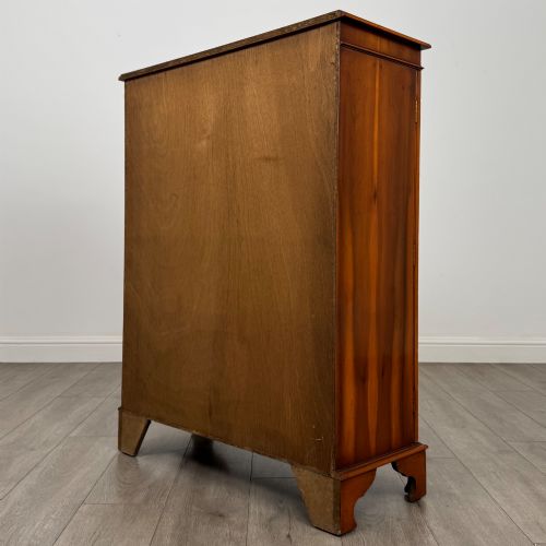 fig 7. An antique yew wood display cabinet featuring two astragal glazed doors with geometric glazing bars, housing books on internal shelves, and resting on bracket feet.