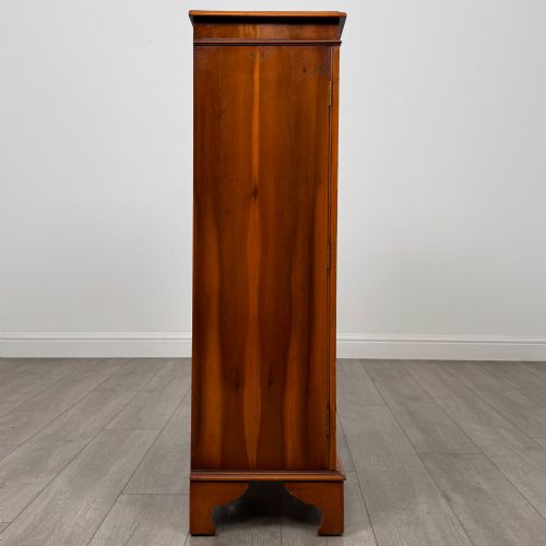 fig 8. An antique yew wood display cabinet featuring two astragal glazed doors with geometric glazing bars, housing books on internal shelves, and resting on bracket feet.