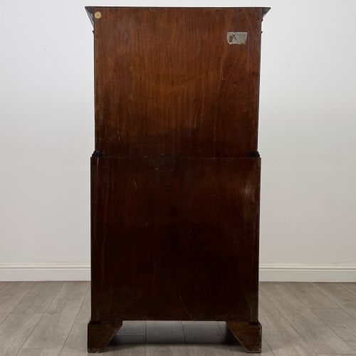 fig 4. A tall 20th-century mahogany serpentine chest of drawers featuring seven graduated drawers with brass handles and bracket feet.