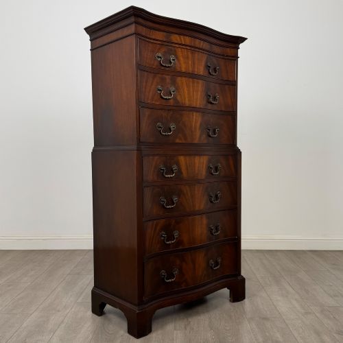 fig 7. A tall 20th-century mahogany serpentine chest of drawers featuring seven graduated drawers with brass handles and bracket feet.