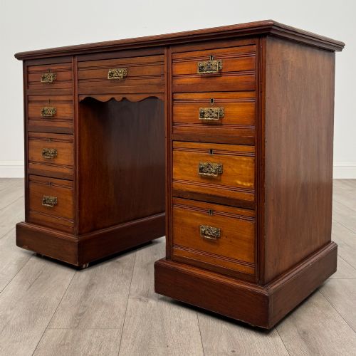 fig 1. An Edwardian mahogany pedestal desk featuring nine reeded drawers with decorative brass drop handles and a central kneehole.