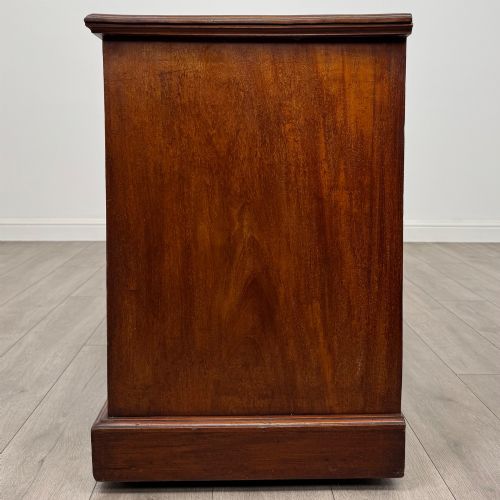 fig 2. An Edwardian mahogany pedestal desk featuring nine reeded drawers with decorative brass drop handles and a central kneehole.