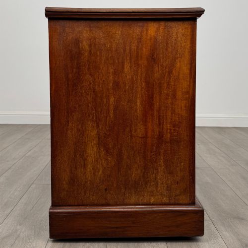 fig 6. An Edwardian mahogany pedestal desk featuring nine reeded drawers with decorative brass drop handles and a central kneehole.