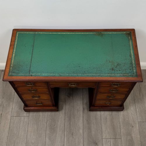 fig 8. An Edwardian mahogany pedestal desk featuring nine reeded drawers with decorative brass drop handles and a central kneehole.