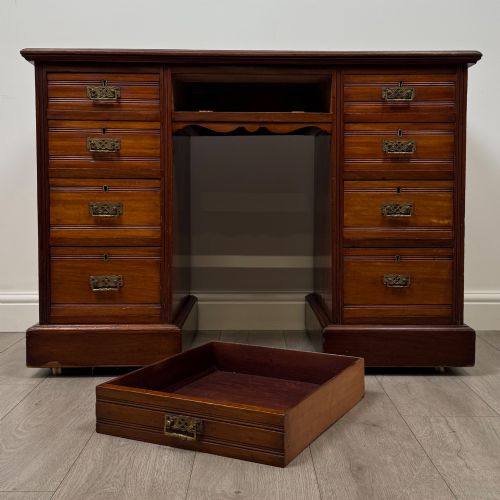 fig 9. An Edwardian mahogany pedestal desk featuring nine reeded drawers with decorative brass drop handles and a central kneehole.
