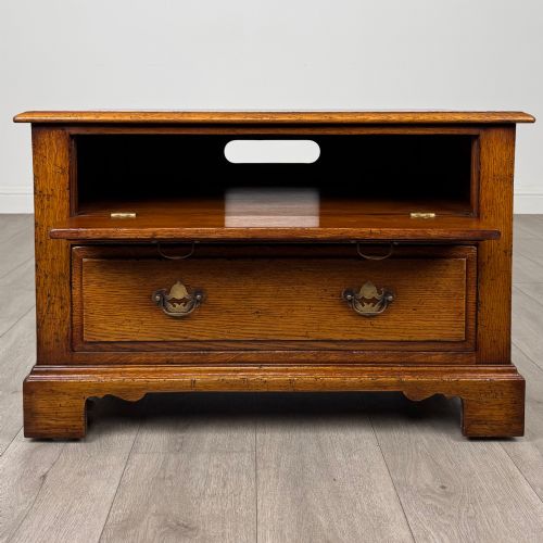 fig 1. A low two-drawer oak chest featuring raised panel fronts, decorative brass drop handles, and bracket feet in a warm brown finish.