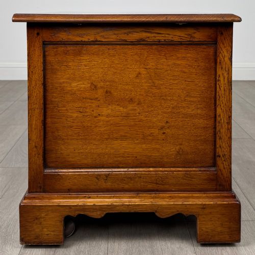 fig 7. A low two-drawer oak chest featuring raised panel fronts, decorative brass drop handles, and bracket feet in a warm brown finish.