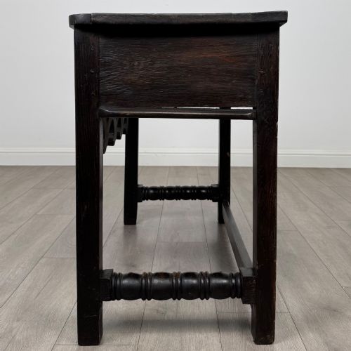 fig 2. A dark oak 19th-century side table featuring floral relief carvings on two drawer fronts, a row of carved cusped arches along the lower apron, and turned side stretchers.