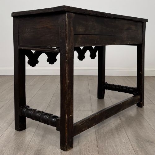 fig 3. A dark oak 19th-century side table featuring floral relief carvings on two drawer fronts, a row of carved cusped arches along the lower apron, and turned side stretchers.