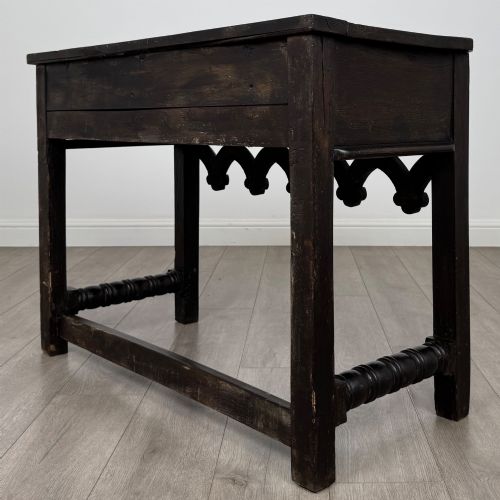 fig 5. A dark oak 19th-century side table featuring floral relief carvings on two drawer fronts, a row of carved cusped arches along the lower apron, and turned side stretchers.