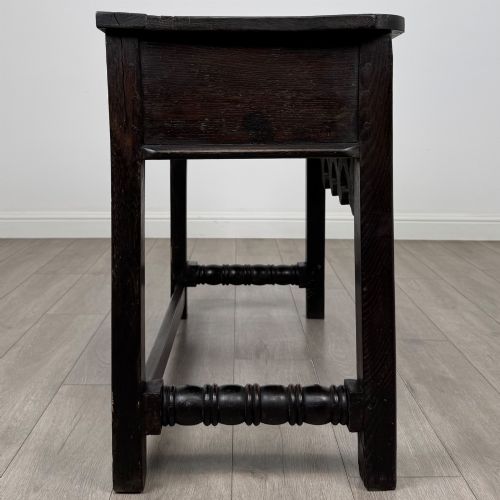 fig 6. A dark oak 19th-century side table featuring floral relief carvings on two drawer fronts, a row of carved cusped arches along the lower apron, and turned side stretchers.