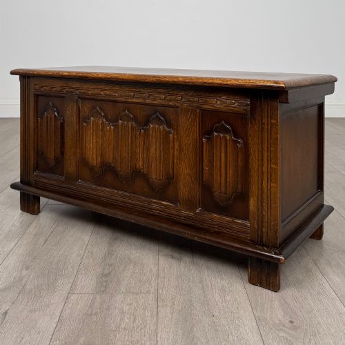 fig 1. A rectangular dark oak blanket box featuring three carved front panels with Gothic arched details and a flat top lid.