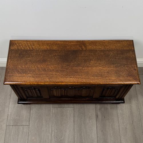 fig 8. A rectangular dark oak blanket box featuring three carved front panels with Gothic arched details and a flat top lid.