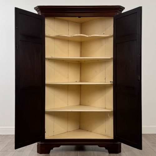 fig 1. A tall 18th-century Georgian dark mahogany corner cabinet featuring panelled double doors, a moulded cornice, and bracket feet.
