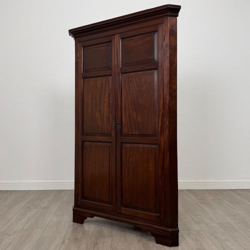 fig 2. A tall 18th-century Georgian dark mahogany corner cabinet featuring panelled double doors, a moulded cornice, and bracket feet.