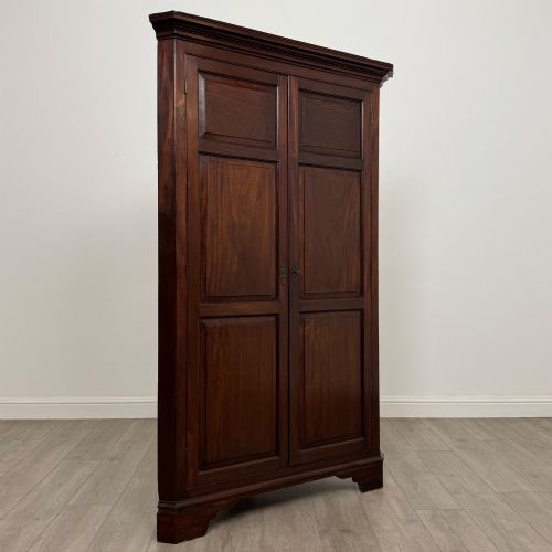 fig 4. A tall 18th-century Georgian dark mahogany corner cabinet featuring panelled double doors, a moulded cornice, and bracket feet.