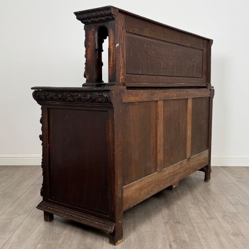 fig 4. A dark oak 19th-century sideboard featuring deep relief carvings of Green Man mythical faces, foliate motifs, lion masks, and an arched upper gallery shelf.