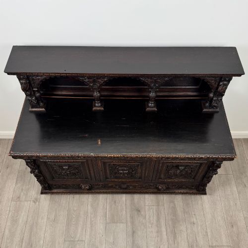fig 9. A dark oak 19th-century sideboard featuring deep relief carvings of Green Man mythical faces, foliate motifs, lion masks, and an arched upper gallery shelf.